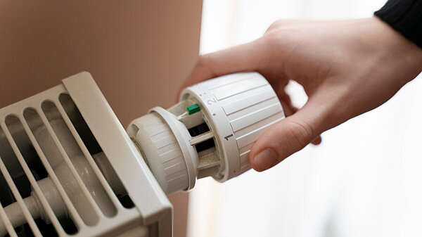 Person adjusting a radiator thermostat