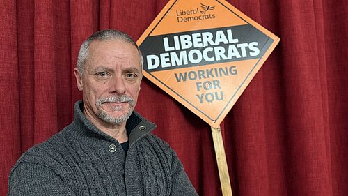 Selected Candidate, Greg Broadhurst standing firmly infront of lib dem poster